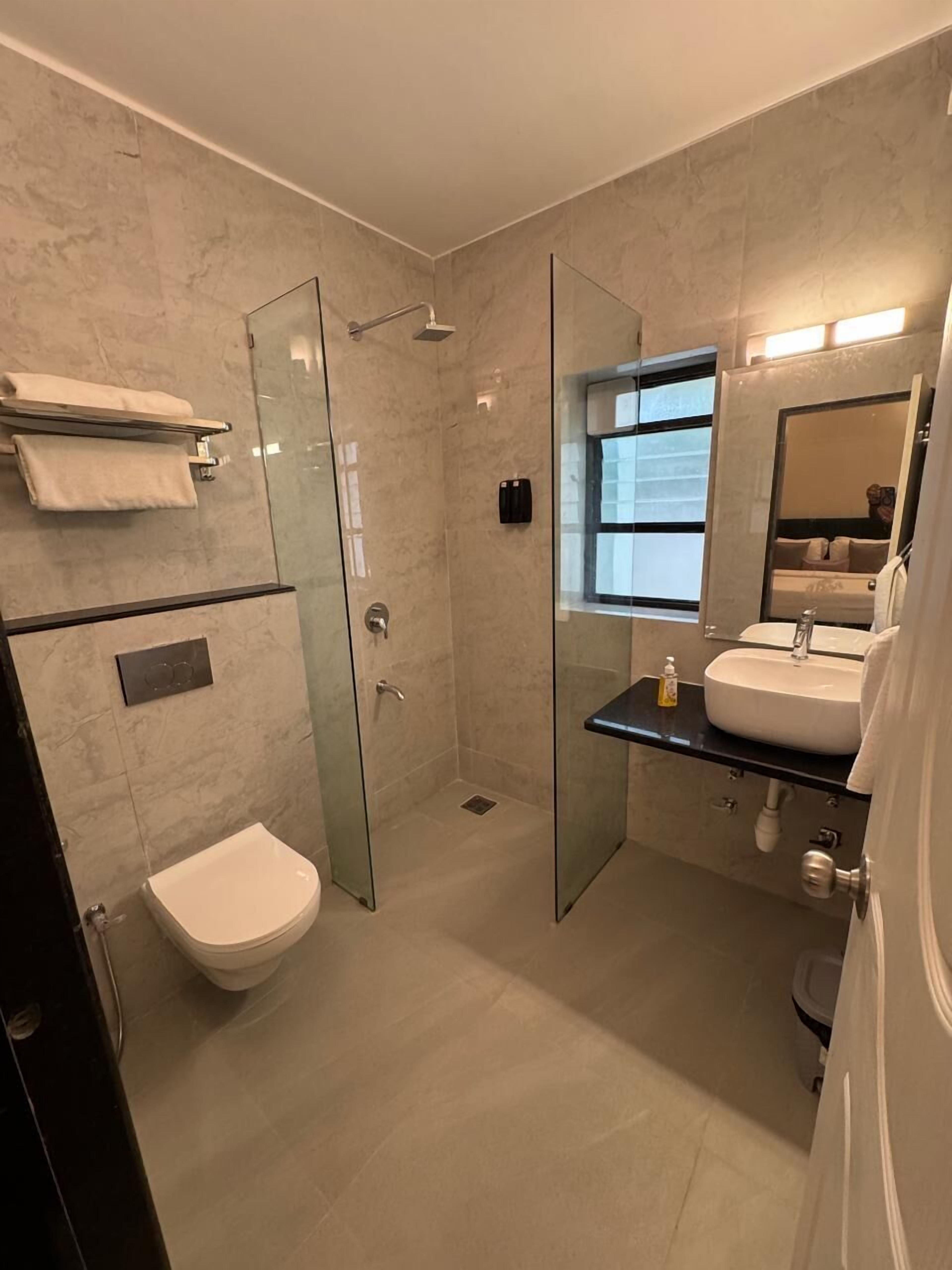 A modern bathroom with a glass-enclosed shower, a white toilet, and a sink with a mirror above it.