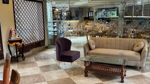 A spacious lobby with a plush sofa, a dark armchair, and a glass coffee table. - Ocean White Sands Resort & Spa (Varca)