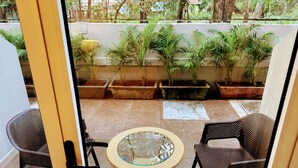 A patio with wicker chairs and a glass-top table, surrounded by potted plants. - Ocean White Sands Resort & Spa (Varca)