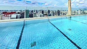 Une piscine sur le toit offrant une vue sur la ville, avec notamment un grand immeuble imposant en évidence.