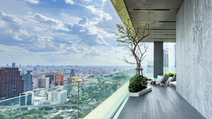 Un balcon moderne offrant une vue sur la ville, doté d’une balustrade en verre et d’un design minimaliste.