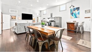 A spacious kitchen with a wooden dining table and chairs, a built-in oven, and a large window.