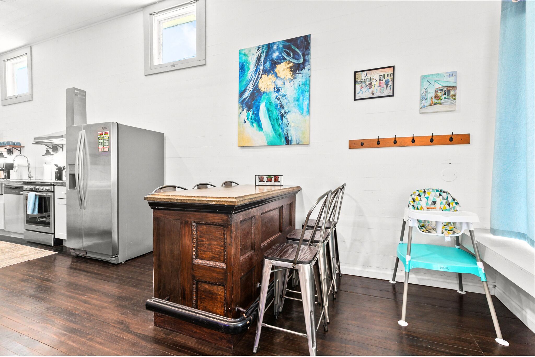 A kitchen with a wooden island, stainless steel appliances, and a high chair.