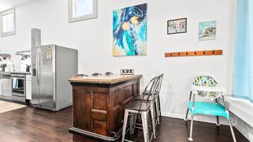 A kitchen with a wooden island, stainless steel appliances, and a high chair.