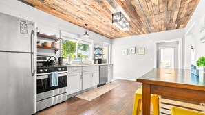 Una cocina moderna con electrodomésticos de acero inoxidable, suelo de madera y techo de madera.