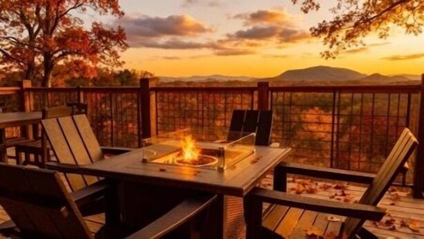 An outdoor seating area with a fire feature, wooden deck, and a view of a mountain range. - MountainSplash: Pool*MtnView*Pets*Games*HotTub*Wifi*FirePit (Sevierville)