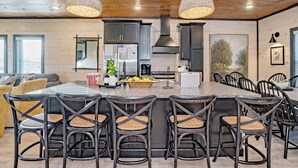 A modern kitchen with a central island, bar stools, and a dining area with chairs. - MtnPlunge@SC: Pool*MtnViews*Theater*Games*Wifi*HotTub*WaterPark*FirePit (Sevierville)