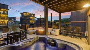 A hot tub area with seating and a view of surrounding buildings. - MtnPlunge@SC: Pool*MtnViews*Theater*Games*Wifi*HotTub*WaterPark*FirePit (Sevierville)
