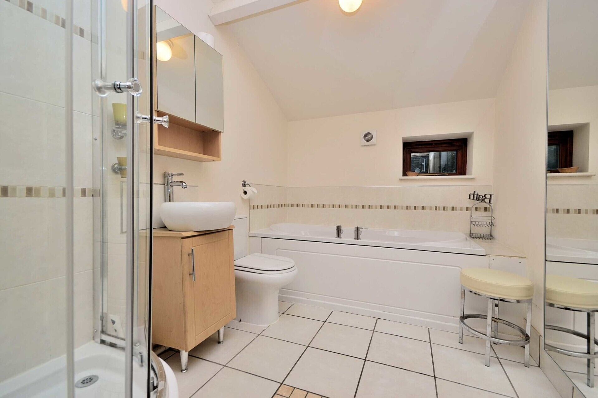 A modern bathroom with a glass shower enclosure, a white sink, a toilet, a bathtub, and a small window.