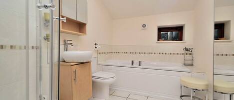 A modern bathroom with a glass shower enclosure, a white sink, a toilet, a bathtub, and a small window.