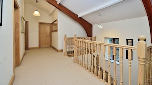 A spacious hallway with a wooden staircase, a wooden door, and a ceiling with exposed beams. - Betws Y Coed Holiday Home by Guestz (Betws-Y-Coed)