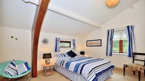 A bedroom with a bed, bedside tables, a chair, a window with curtains, and a picture on the wall. - Betws Y Coed Holiday Home by Guestz (Betws-Y-Coed)