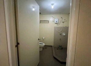 Un baño pequeño y funcional con inodoro, zona de ducha y secador de manos.