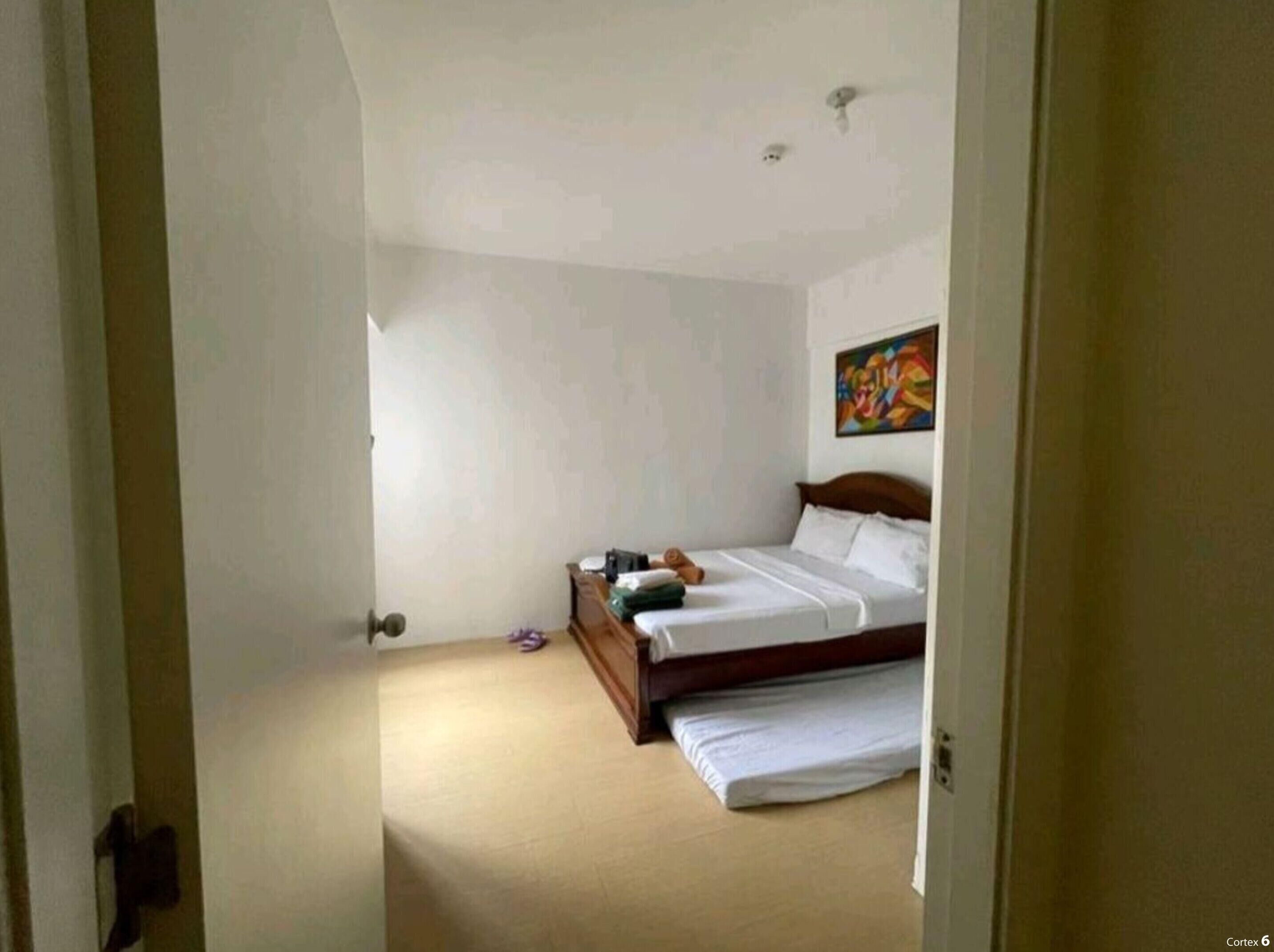 A bedroom with a bed, a painting on the wall, and a door leading to another room.