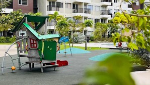 A playground with a green house structure, a blue slide, and a red ramp. - Cozy Staycation at Avida Iloilo (Iloilo)