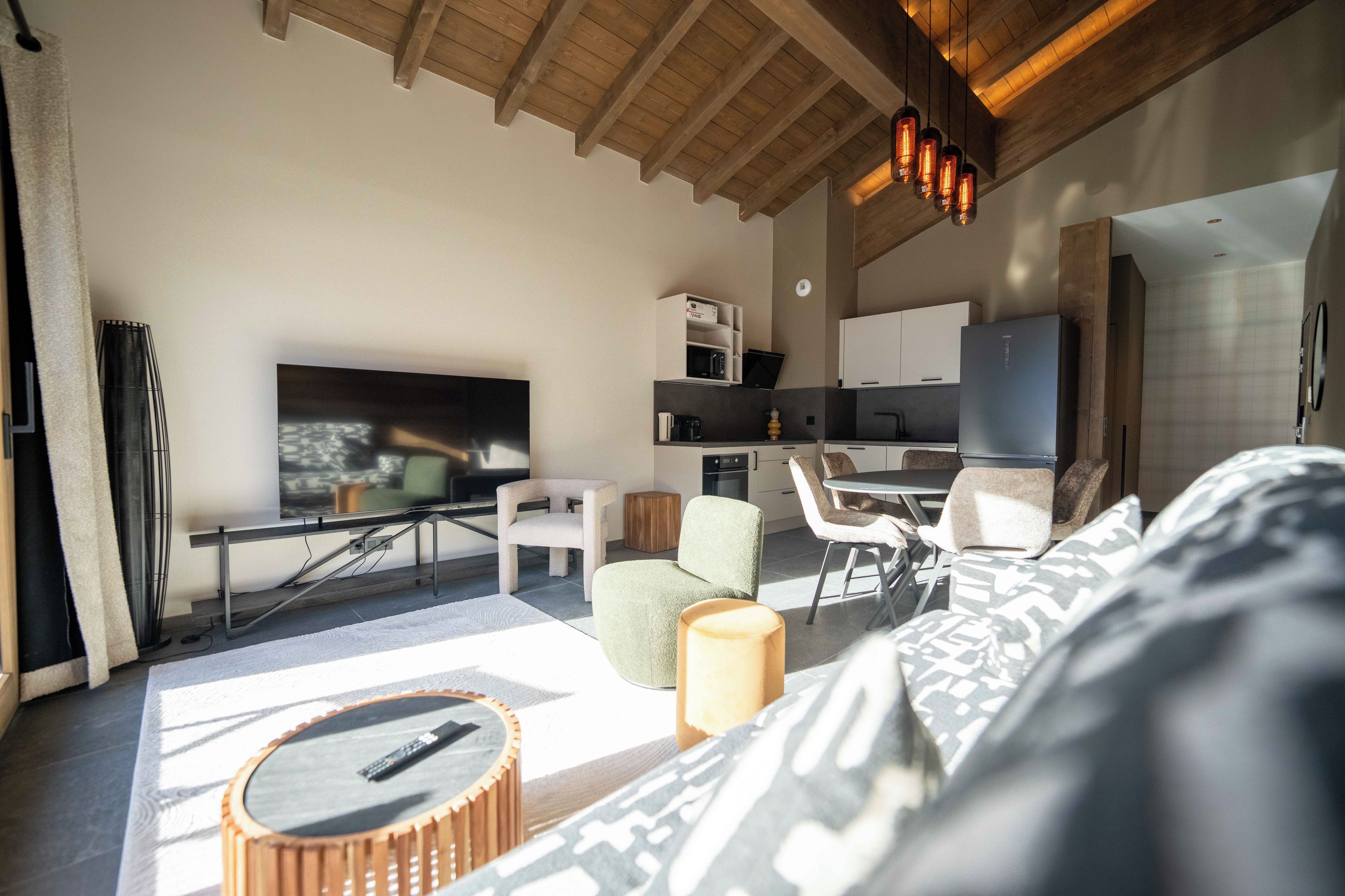 Un salon moderne avec un téléviseur à écran plat, un canapé, une table basse et un coin repas avec des chaises.