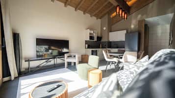 Un salon moderne avec un téléviseur à écran plat, un canapé, une table basse et un coin repas avec des chaises.