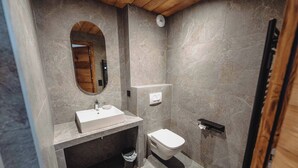 A modern bathroom with a marble floor, a wooden-framed mirror, a white sink, and a toilet. - Le Cairne Residence (La Chapelle-d'Abondance)