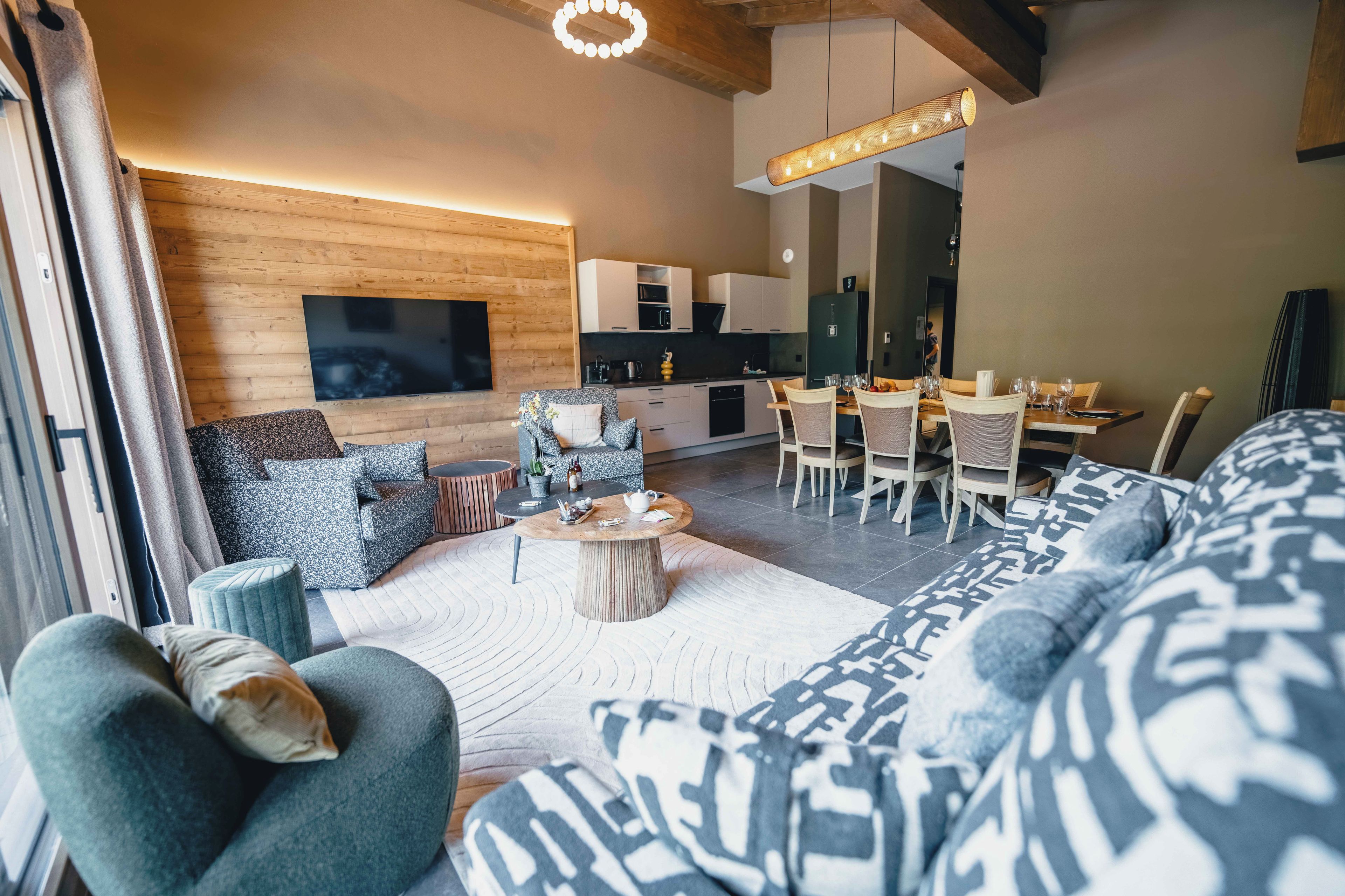 Ein modernes Wohnzimmer mit einer großen Couch, einem Couchtisch und einem an der Wand montierten Fernseher.