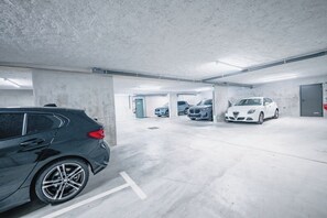 Un aparcamiento con varios coches estacionados, pilares de hormigón y un ambiente limpio y bien iluminado.
