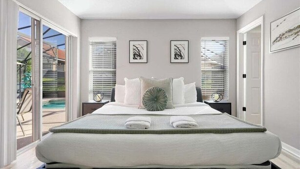 Een moderne slaapkamer met een groot bed, twee nachtkastjes en uitzicht op een zwembad.