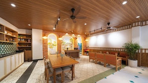 A restaurant with wooden furniture, a tiled floor, and a ceiling fan. - Sujet Center Hotel by Haviland  (Da Nang)