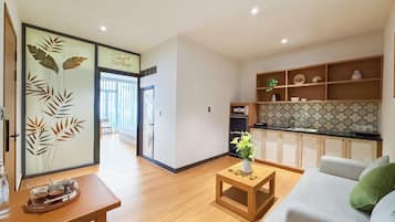 Uma sala de estar moderna com sofá, mesa de centro e área de cozinha com armários e bancada.