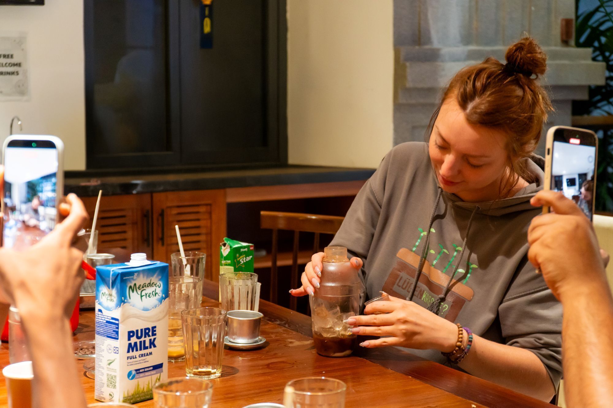 Una persona sentada a una mesa con un cartón de leche, vasos y una botella.