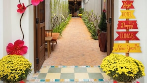 A corridor with a checkered floor, a wooden pergola, and hanging lanterns. - Sujet Center Hotel by Haviland  (Da Nang)