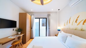 A hotel room with a bed, a desk, a chair, a TV, a ceiling fan, and a view of the outside. - Sujet Center Hotel by Haviland  (Da Nang)