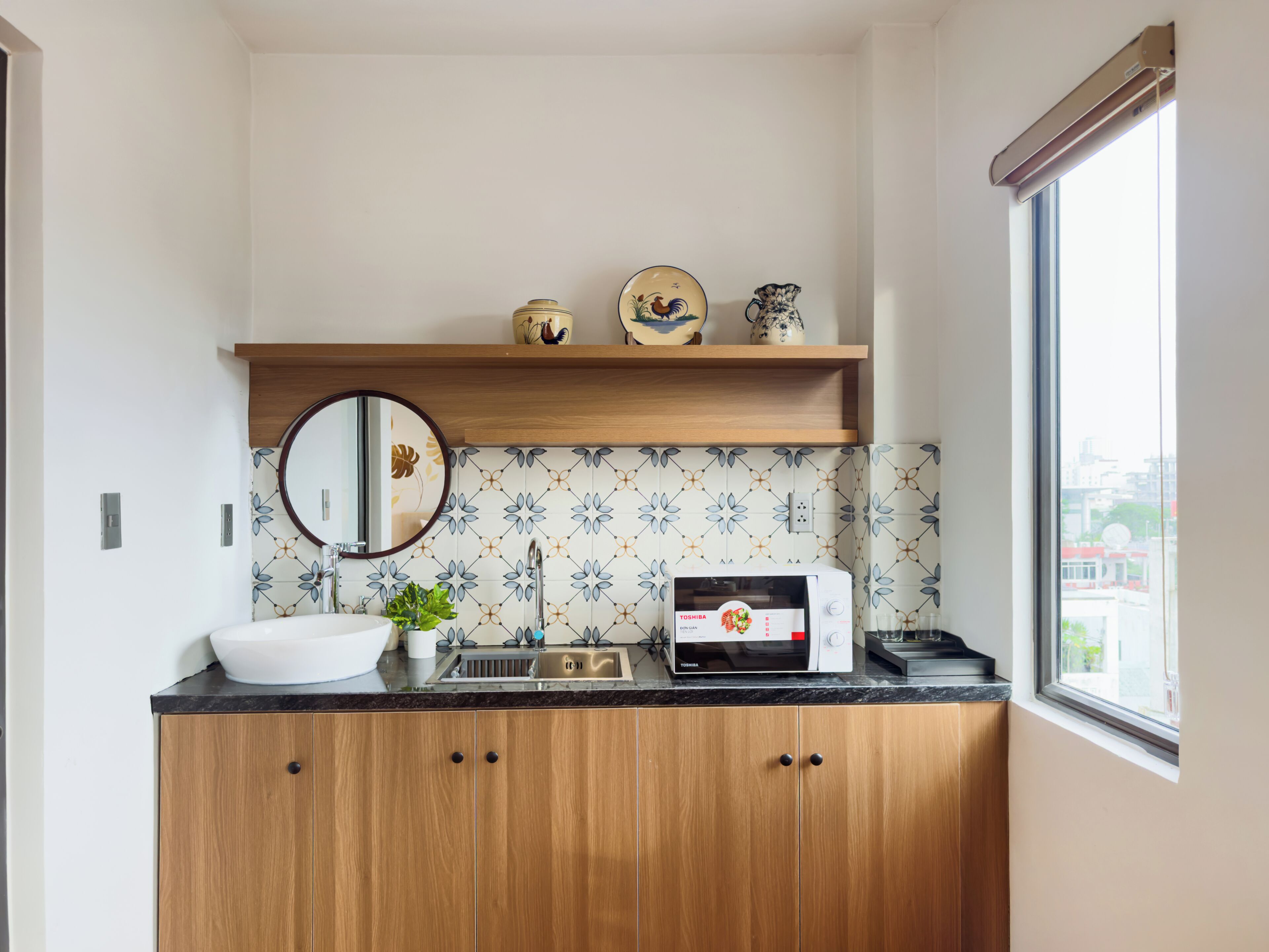 Una cocina con microondas, fregadero y armarios de madera.
