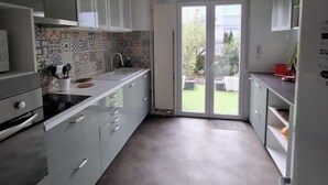 A narrow kitchen with white cabinets, a tiled backsplash, and a sliding glass door leading to a patio.