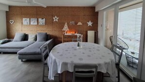 A modern living room with a sofa, a round dining table, and a fireplace.
