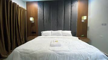 A neatly made bed with white linens, two bedside lamps, and a wooden headboard.