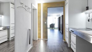 Een moderne keuken met roestvrijstalen apparatuur, een houten vloer en een gang naar een woonruimte.