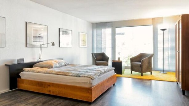 Een moderne slaapkamer met een groot bed, een bureau, twee stoelen en uitzicht op de omgeving.