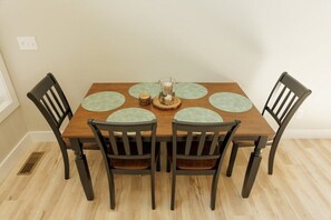 A dining table with four chairs, a central candle holder, and a decorative coaster set. - Mabel's Place - 3BR, 2.5BA, Newly Renovated Duplex (Waynesville)