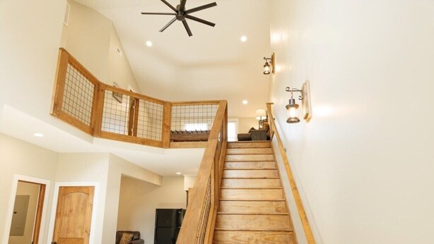 A multi-level interior with a wooden staircase, a ceiling fan, and wall-mounted lighting. - Mabel's Place - 3BR, 2.5BA, Newly Renovated Duplex (Waynesville)
