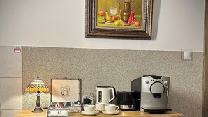 Un escritorio de madera con una cafetera, tazas y una lámpara.
