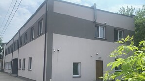 Un edificio moderno con fachada plana, varias ventanas y una pequeña puerta de entrada.