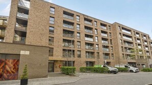 Un edificio in mattoni di più piani con tetto piatto, ampie finestre e balconi.