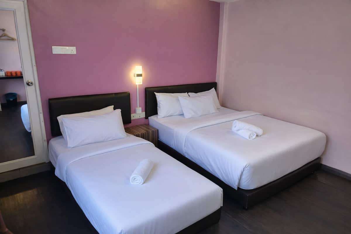 Ein Hotelzimmer mit zwei Einzelbetten, einem Nachttisch mit Lampe und einer Tür zu einem Badezimmer.
