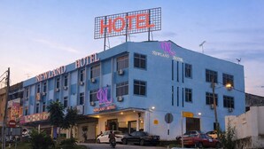 A hotel with a prominent neon sign, multiple air conditioning units, and a visible entrance.