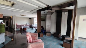 A spacious lobby with a seating area, a reception desk, and a view of the kitchen area.