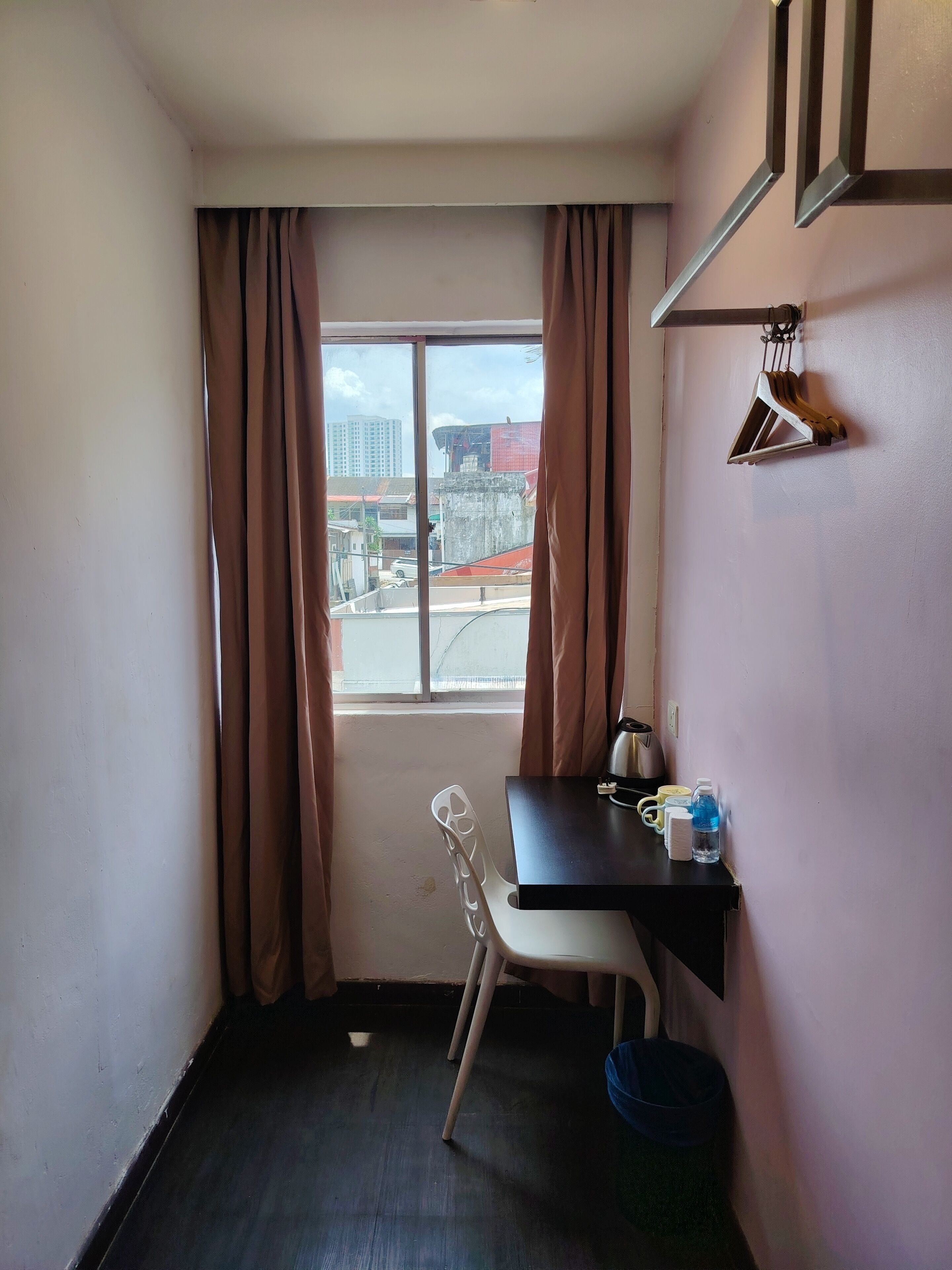 A small room with a window, a desk, a chair, and a water bottle.