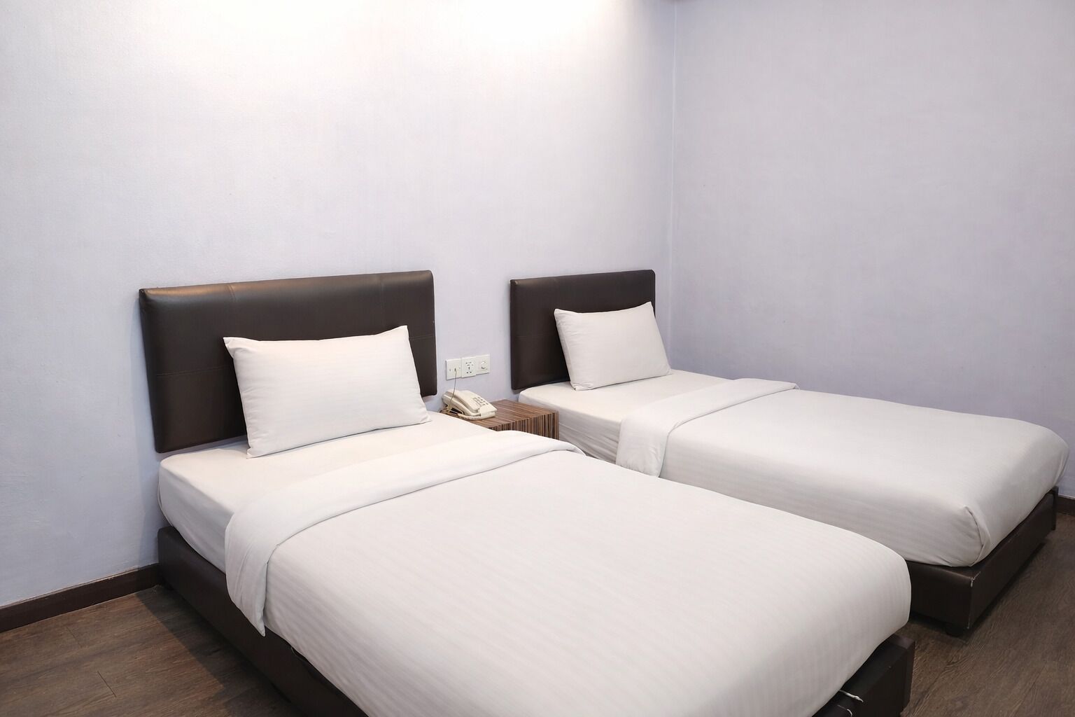 Two single beds with dark headboards, white bedding, and a bedside phone.