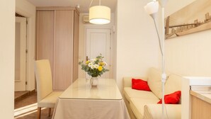 A modern living room with a dining table, a sofa, and a vase of flowers. - Golden Hour Studio - Steps to the Sea - A/C + WiFi (Málaga)