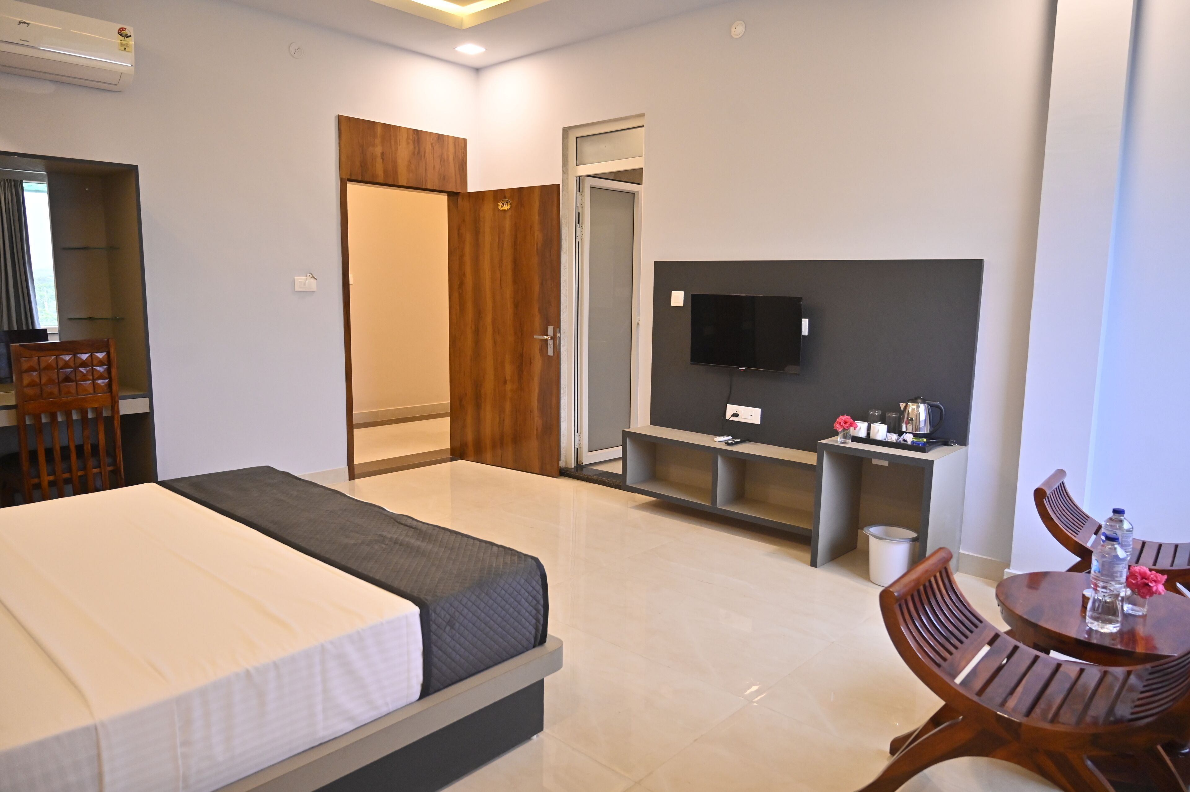 Une chambre d’hôtel avec un lit, une télévision, une petite table avec des chaises et une armoire en bois.
