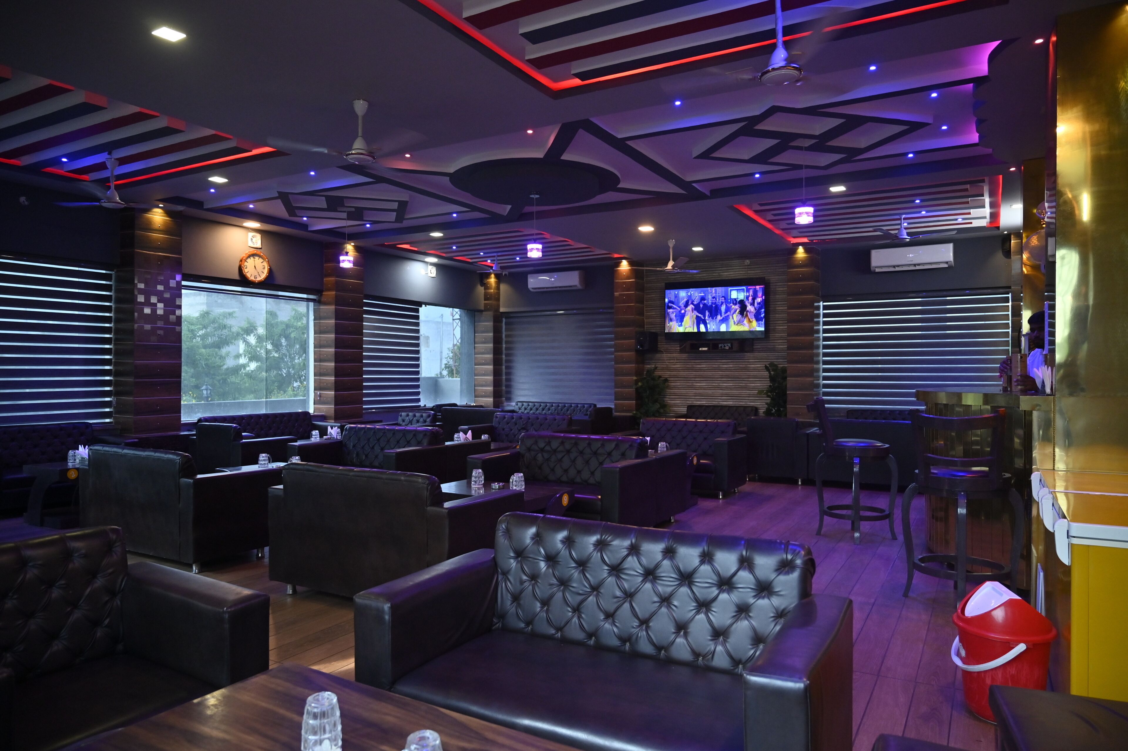 A modern lounge area with leather seating, a television screen, and ambient lighting.