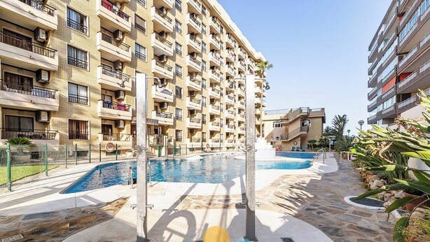 A multi-story residential building with balconies, a swimming pool, and a stone-tiled patio area. - 76 – Cozy Beachfront Apartment with Pool in Fuengirola (Fuengirola)